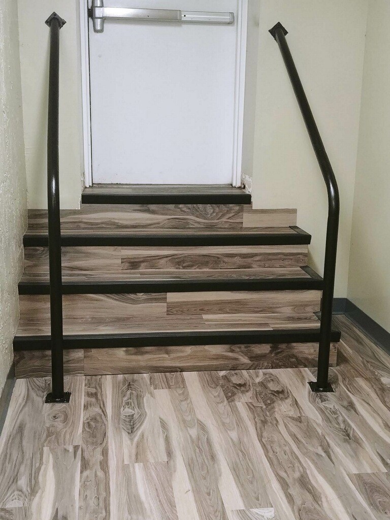 stairs leading to exit door with wood grain floors