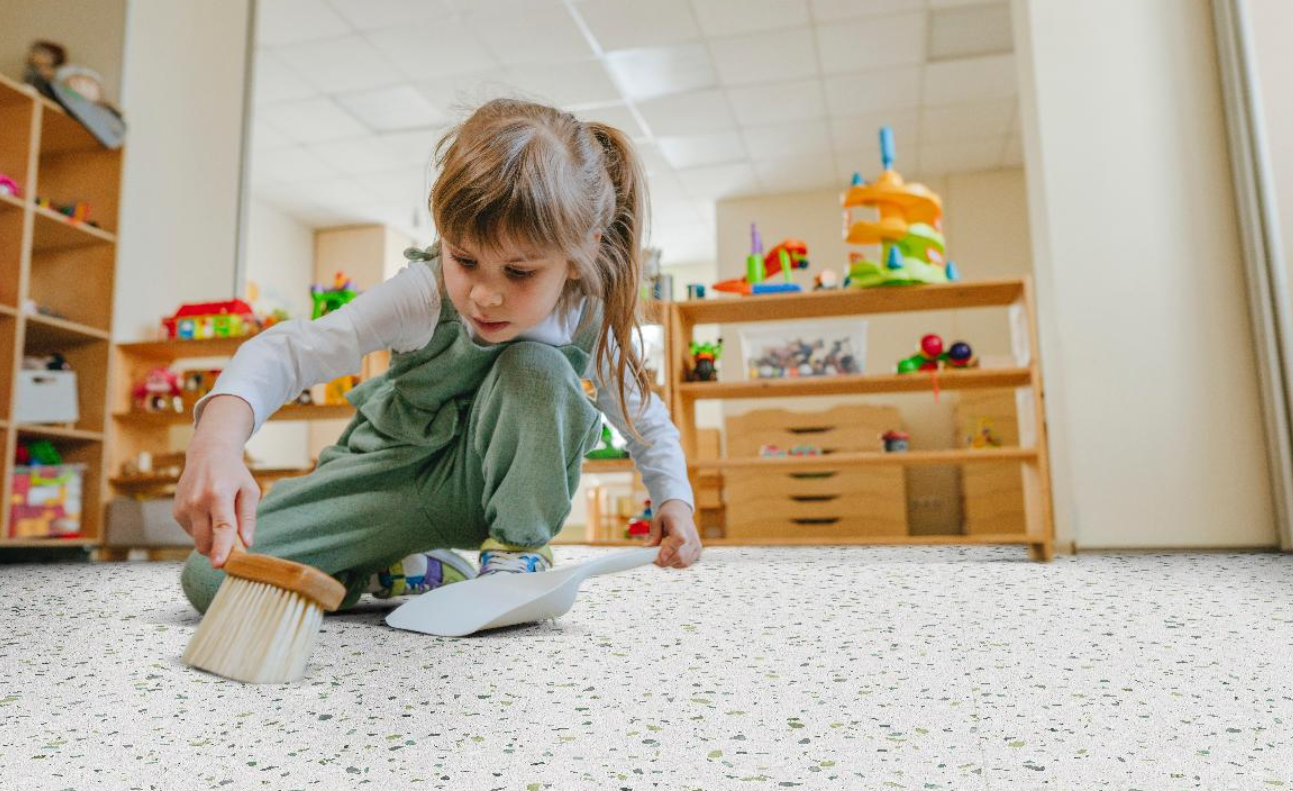 Child on the floor of a school room, cleaning up a mess